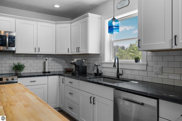 6330 Lund Rd SW, Fife Lake, MI 49633 - kitchen with stainless steel appliances, butcher block countertops, white cabinetry, hanging light fixtures, and decorative backsplash
