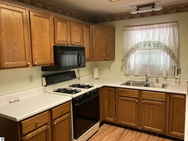 653 S Morrison Rd, West Branch, MI 48661 - kitchen with range with gas cooktop, black microwave, and brown cabinetry