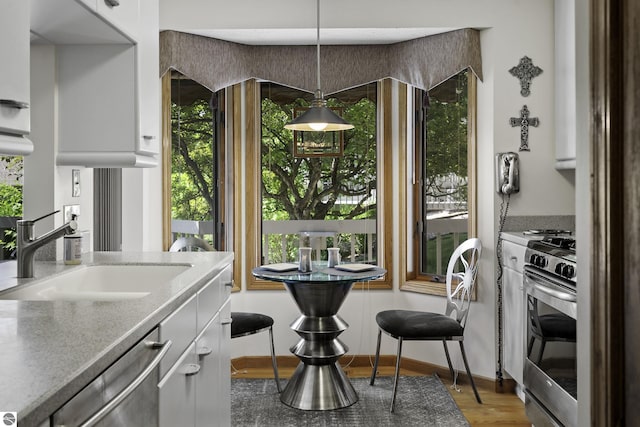 3810 Ridgeway Pl, Traverse City, MI 49684 - kitchen featuring stainless steel appliances, white cabinets, pendant lighting, light stone counters, and wood finished floors
