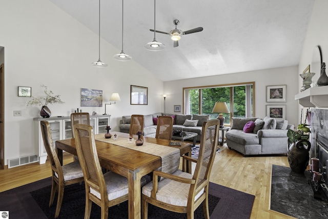3810 Ridgeway Pl, Traverse City, MI 49684 - dining room featuring a ceiling fan, wood finished floors, high vaulted ceiling, and a fireplace