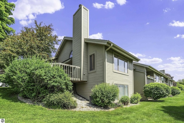 3810 Ridgeway Pl, Traverse City, MI 49684 - view of side of property with a chimney, a lawn, and a deck