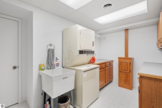3810 Ridgeway Pl, Traverse City, MI 49684 - laundry area with stacked washer / drying machine, cabinet space, and light tile patterned floors