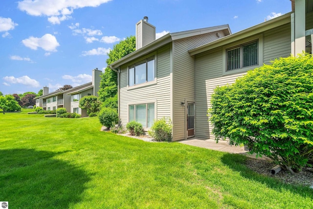 3810 Ridgeway Pl, Traverse City, MI 49684 - back of house featuring a chimney and a lawn