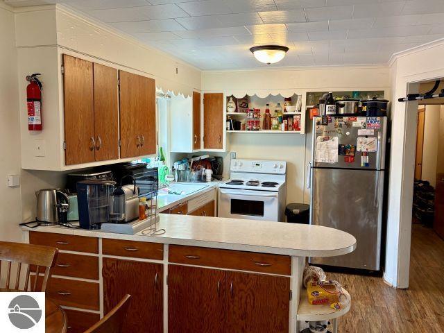 180 S Benzie Blvd, Beulah, MI 49617 - kitchen with freestanding refrigerator, white electric range oven, open shelves, light countertops, and wood finished floors
