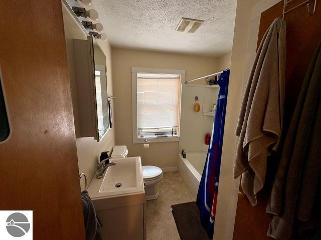 180 S Benzie Blvd, Beulah, MI 49617 - bathroom with a textured ceiling, shower / tub combo with curtain, and vanity