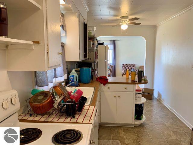 180 S Benzie Blvd, Beulah, MI 49617 - kitchen featuring white range oven, tile countertops, open shelves, a peninsula, and white cabinets