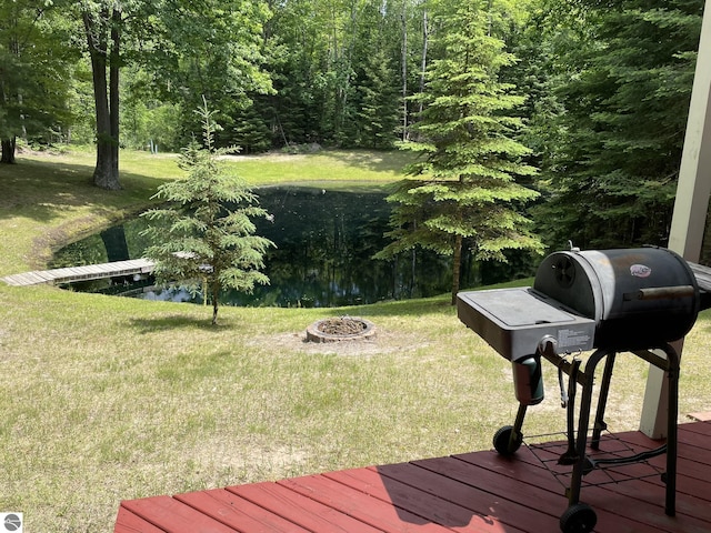 5218 E Laird Lake Rd, Hale, MI 48739 - wooden deck featuring area for grilling, an outdoor fire pit, a yard, and a forest view