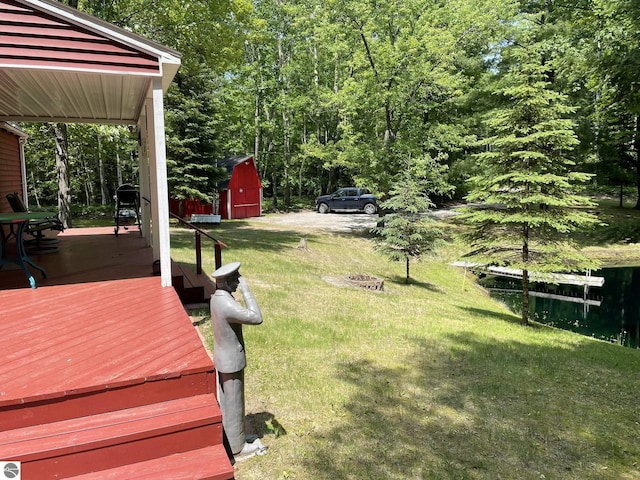 5218 E Laird Lake Rd, Hale, MI 48739 - view of grassy yard with a storage unit and a deck with water view