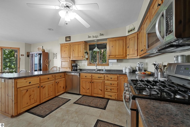 6387 W Maple St, Lake City, MI 49651 - kitchen with stainless steel appliances, a peninsula, ceiling fan, light tile patterned floors, and brown cabinetry