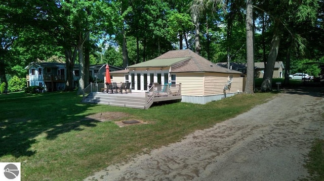 7600 Maple St, Grawn, MI 49637 - back of house with a wooden deck, a yard, view of wooded area, and dirt driveway