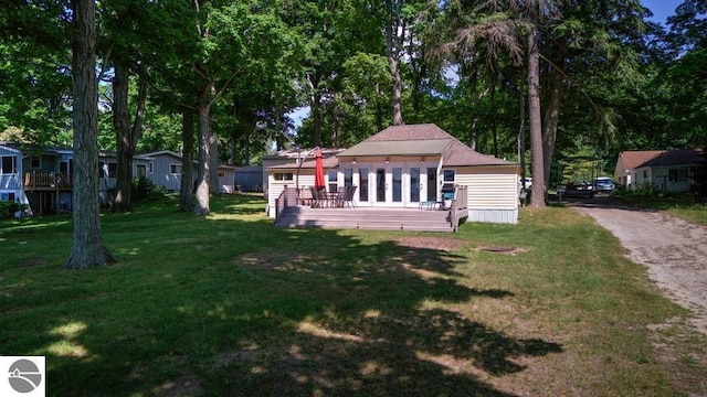 7600 Maple St, Grawn, MI 49637 - view of green lawn with a wooden deck, driveway, and view of scattered trees