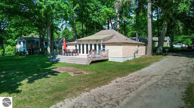 7600 Maple St, Grawn, MI 49637 - back of property featuring a wooden deck, a lawn, view of wooded area, and dirt driveway