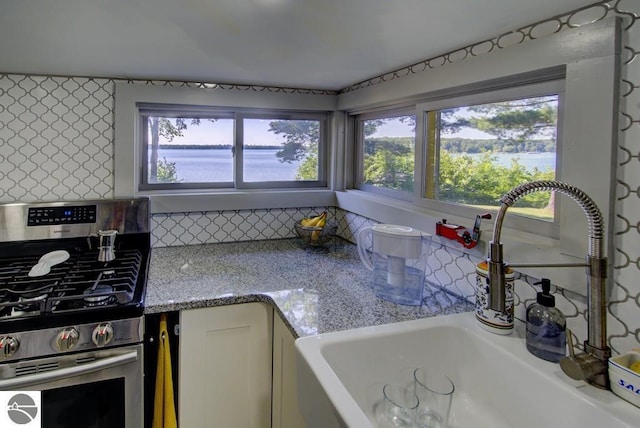 7600 Maple St, Grawn, MI 49637 - kitchen with gas range, tasteful backsplash, and light stone countertops