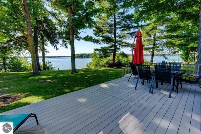 7600 Maple St, Grawn, MI 49637 - deck featuring a water view, outdoor dining space, and a lawn