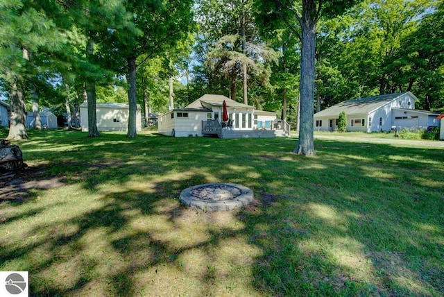 7600 Maple St, Grawn, MI 49637 - view of grassy yard with a wooden deck, an outdoor fire pit, and view of scattered trees
