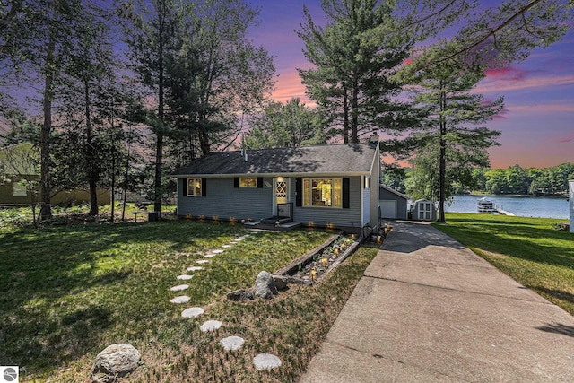 8781 Clam Lake Rd, Bellaire, MI 49615 - view of front of house with an outdoor structure, a front lawn, a water view, and a detached garage