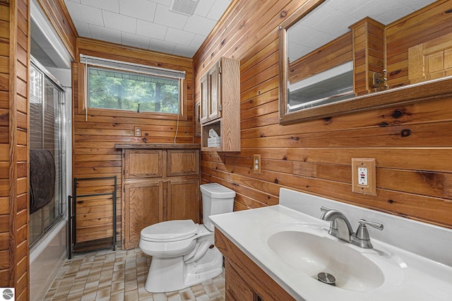 8781 Clam Lake Rd, Bellaire, MI 49615 - bathroom featuring wood walls, vanity, and combined bath / shower with glass door