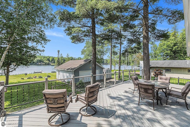 8781 Clam Lake Rd, Bellaire, MI 49615 - deck with a water view, outdoor dining area, an outbuilding, and a lawn