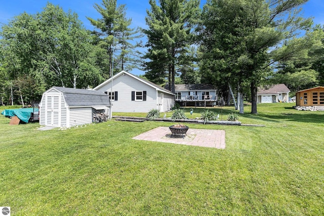 8781 Clam Lake Rd, Bellaire, MI 49615 - view of grassy yard with an outdoor fire pit, a storage shed, and a patio