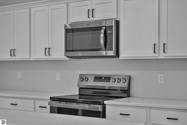 6483 Jeffrey Pl, Grawn, MI 49637 - kitchen with appliances with stainless steel finishes, white cabinets, and light countertops