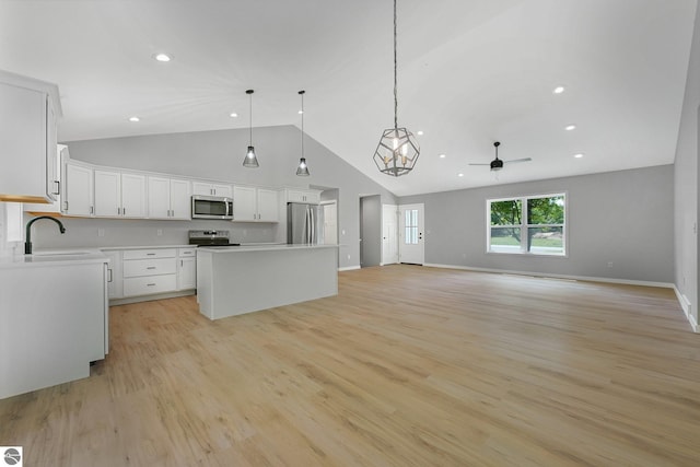 6483 Jeffrey Pl, Grawn, MI 49637 - kitchen featuring appliances with stainless steel finishes, a ceiling fan, a center island, white cabinets, and hanging light fixtures
