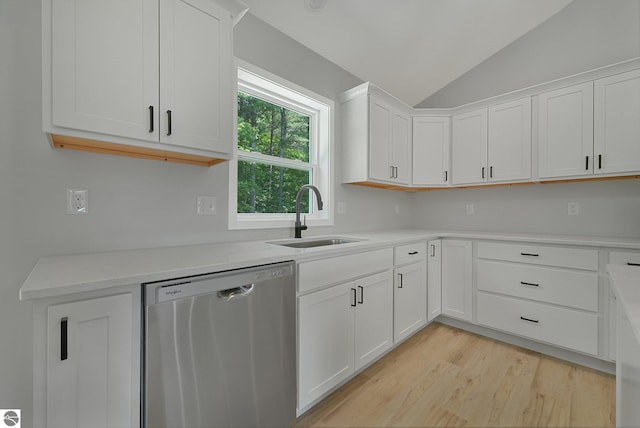 6483 Jeffrey Pl, Grawn, MI 49637 - kitchen featuring stainless steel dishwasher, vaulted ceiling, white cabinetry, light wood-style floors, and light countertops