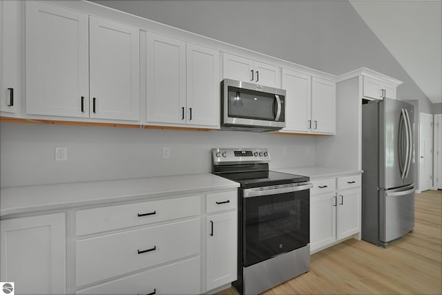 6483 Jeffrey Pl, Grawn, MI 49637 - kitchen featuring stainless steel appliances, light wood finished floors, light countertops, white cabinets, and vaulted ceiling