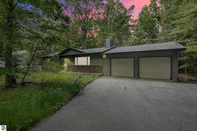 10085 Harmony Dr, Interlochen, MI 49643 - view of front of house with an attached garage, driveway, a chimney, and a shingled roof