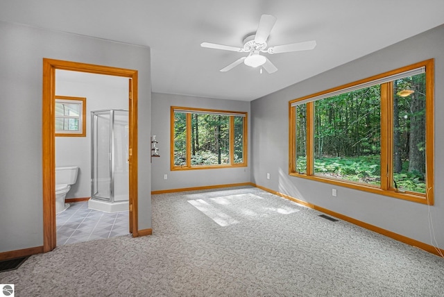 10085 Harmony Dr, Interlochen, MI 49643 - unfurnished bedroom with multiple windows, carpet flooring, ensuite bath, and ceiling fan
