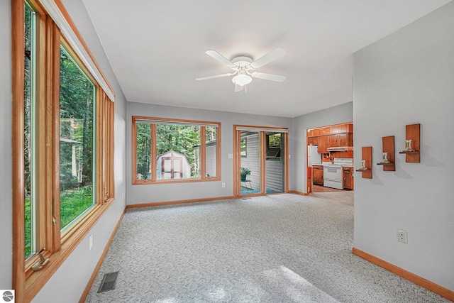 10085 Harmony Dr, Interlochen, MI 49643 - unfurnished living room with healthy amount of natural light, light carpet, and a ceiling fan
