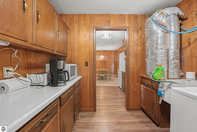 10085 Harmony Dr, Interlochen, MI 49643 - washroom with wood walls, light wood finished floors, a textured ceiling, and washer / clothes dryer
