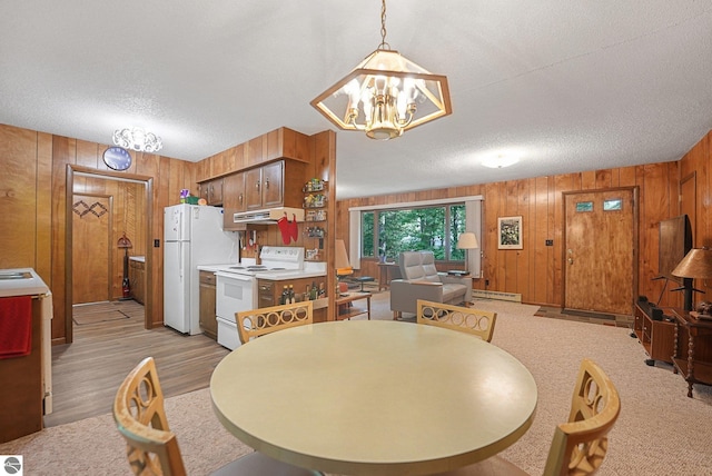 10085 Harmony Dr, Interlochen, MI 49643 - dining room featuring wood walls, a textured ceiling, a baseboard heating unit, a chandelier, and light wood-style flooring