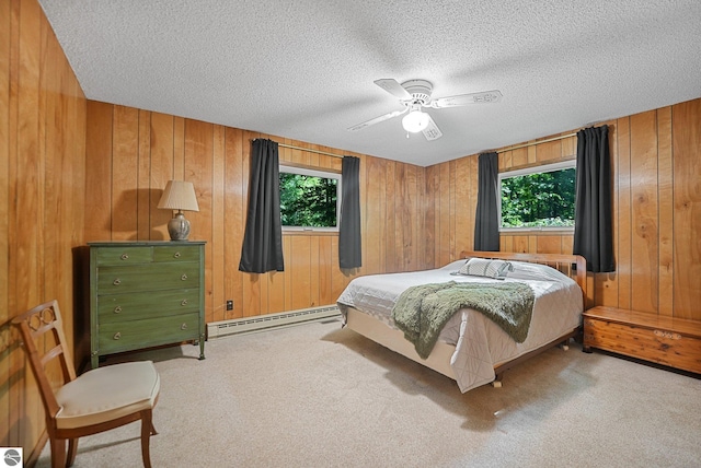 10085 Harmony Dr, Interlochen, MI 49643 - carpeted bedroom with baseboard heating, wood walls, a textured ceiling, and ceiling fan
