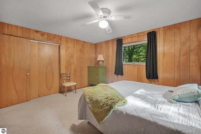 10085 Harmony Dr, Interlochen, MI 49643 - carpeted bedroom with wood walls, a textured ceiling, ceiling fan, and a closet