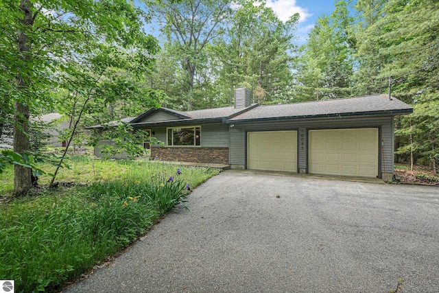 10085 Harmony Dr, Interlochen, MI 49643 - view of front of home featuring a garage, a chimney, and asphalt driveway
