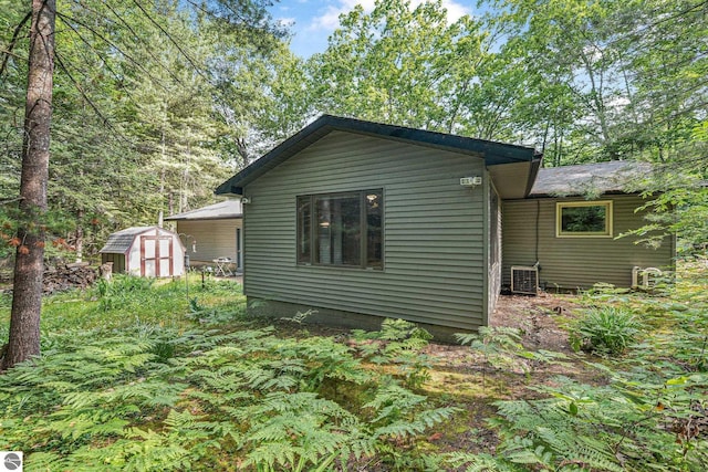10085 Harmony Dr, Interlochen, MI 49643 - view of home's exterior with a storage unit and a cooling unit