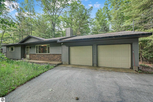 10085 Harmony Dr, Interlochen, MI 49643 - ranch-style house with a chimney, a garage, brick siding, and asphalt driveway