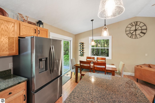 8315 Aimee Ln, Lake Ann, MI 49650 - kitchen featuring stainless steel fridge, light wood finished floors, lofted ceiling, pendant lighting, and dark stone countertops
