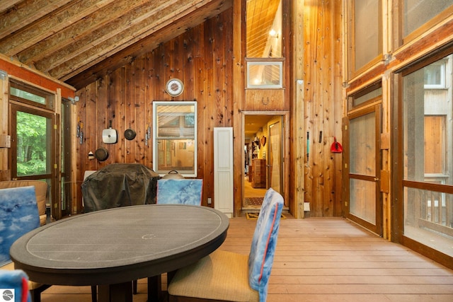15910 E Cherry Park Dr, Northport, MI 49670 - dining area with light wood-style flooring, wooden walls, and high vaulted ceiling