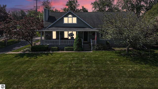 699 Harbor Dr, Manistee, MI 49660 - view of front facade featuring a porch, a lawn, a chimney, and a shingled roof