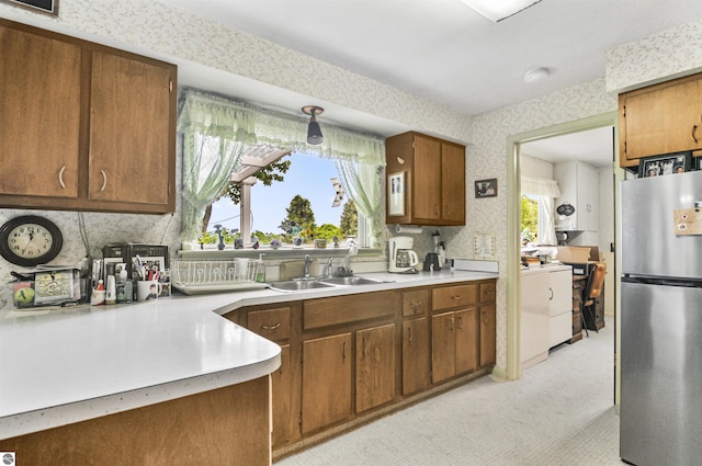 611 Sunset Ln, Cadillac, MI 49601 - kitchen with freestanding refrigerator, wallpapered walls, light countertops, washer / dryer, and brown cabinetry