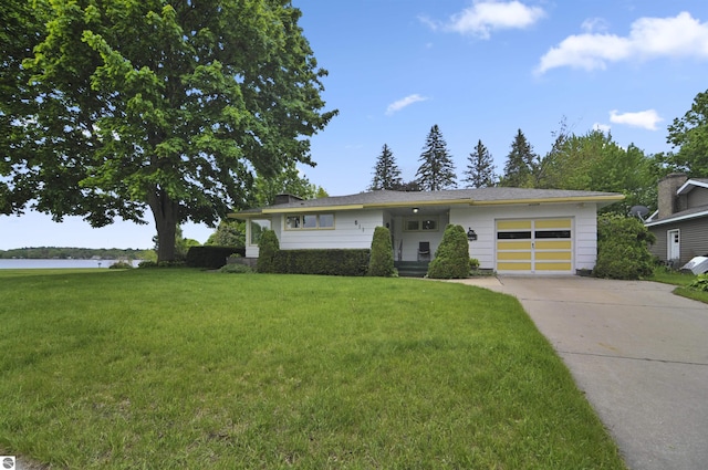 611 Sunset Ln, Cadillac, MI 49601 - view of front facade with an attached garage, driveway, a front lawn, and a water view