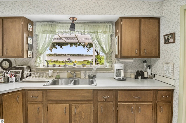 611 Sunset Ln, Cadillac, MI 49601 - kitchen featuring light countertops, wallpapered walls, and brown cabinetry