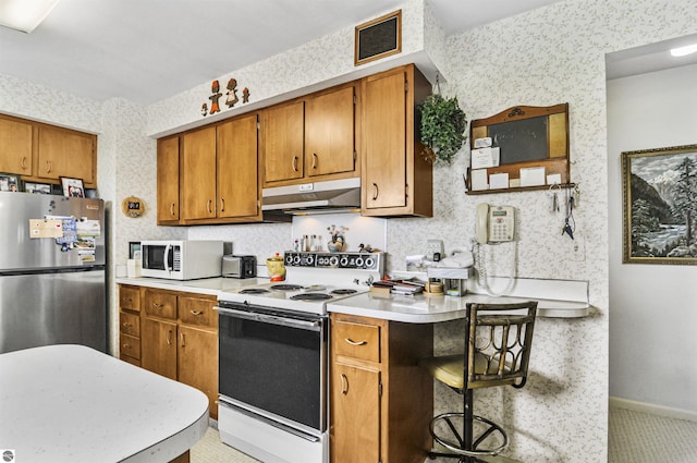 611 Sunset Ln, Cadillac, MI 49601 - kitchen featuring white appliances, wallpapered walls, under cabinet range hood, light countertops, and brown cabinets