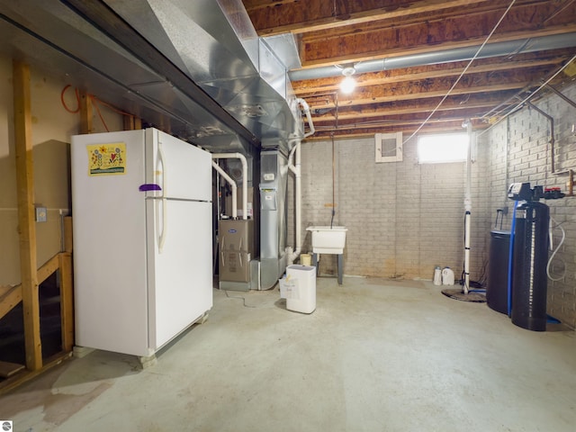 318 Red Maple Ln, Shepherd, MI 48883 - basement featuring freestanding refrigerator, a water softener system, heating unit, and brick wall