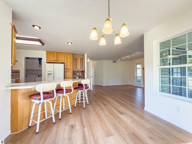 318 Red Maple Ln, Shepherd, MI 48883 - kitchen featuring white refrigerator with ice dispenser, washing machine and clothes dryer, light wood-style flooring, a chandelier, and recessed lighting