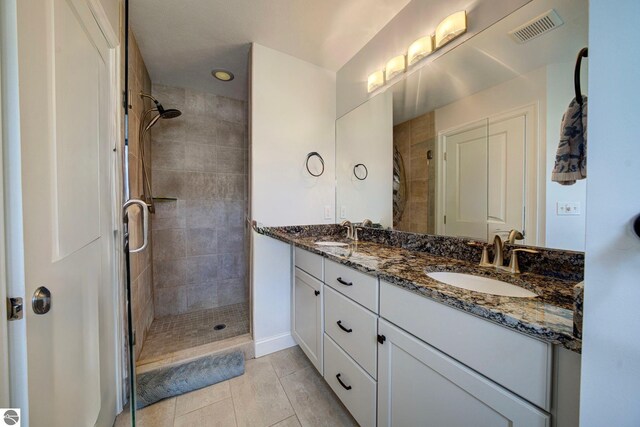 982 Lake Ridge Dr Unit 10, Traverse City, MI 49684 - bathroom with a tile shower, double vanity, and tile patterned floors