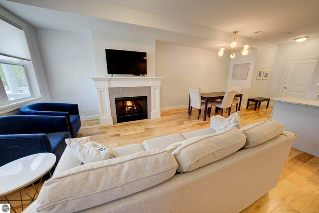 982 Lake Ridge Dr Unit 10, Traverse City, MI 49684 - living room with light wood finished floors, a tile fireplace, and a chandelier