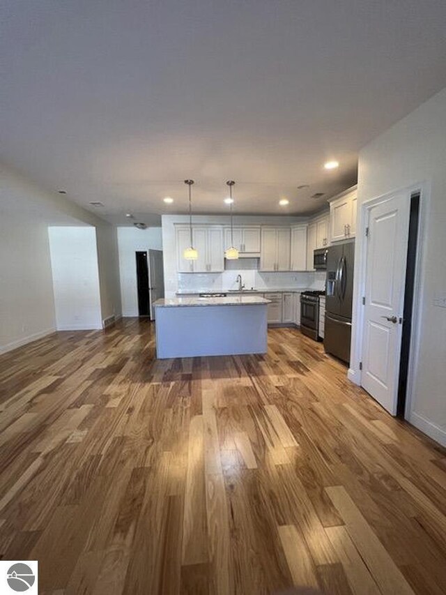 982 Lake Ridge Dr Unit 10, Traverse City, MI 49684 - kitchen with appliances with stainless steel finishes, wood finished floors, open floor plan, decorative light fixtures, and recessed lighting
