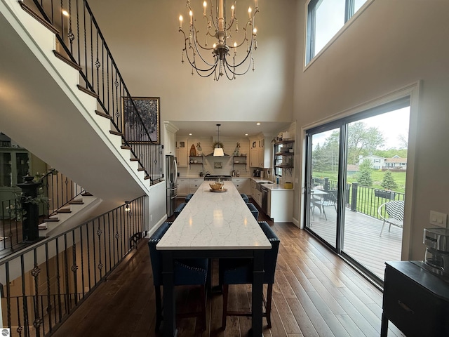 777 Stoneridge Dr, Mount Pleasant, MI 48858 - dining space featuring dark wood finished floors, a chandelier, stairs, and a towering ceiling